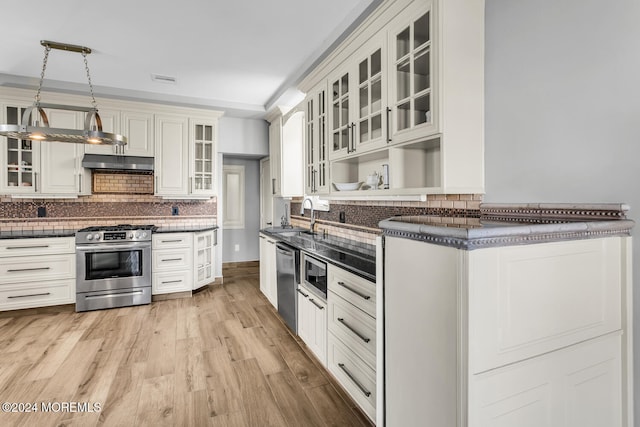 kitchen featuring sink, decorative light fixtures, light wood-type flooring, appliances with stainless steel finishes, and backsplash