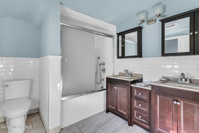 full bathroom featuring tile walls, vanity, shower / bath combination with glass door, and toilet