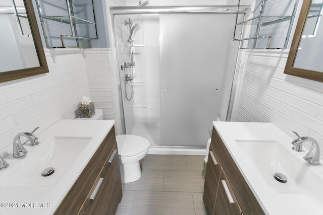 bathroom featuring tile patterned floors, toilet, an enclosed shower, tile walls, and vanity