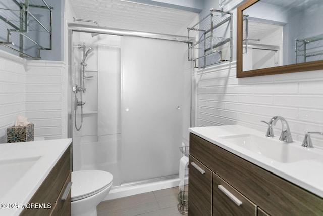 bathroom with a shower with door, vanity, tile patterned floors, and toilet