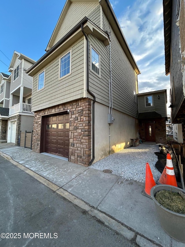 view of side of home with a garage, stone siding, and driveway