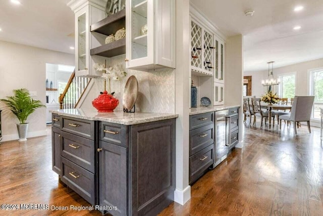 kitchen with pendant lighting, white cabinets, dark hardwood / wood-style floors, light stone countertops, and tasteful backsplash