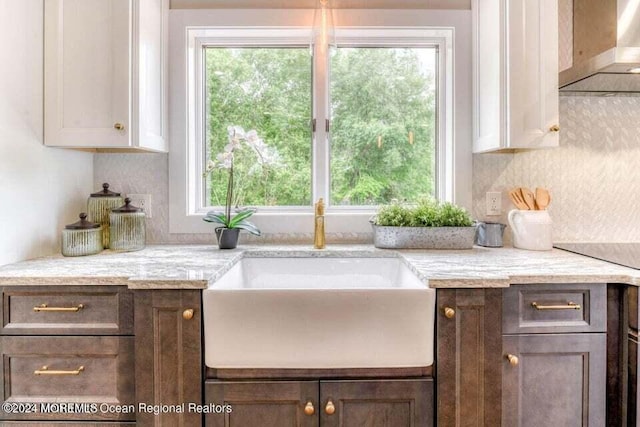 kitchen featuring a wealth of natural light, white cabinetry, dark brown cabinets, and wall chimney exhaust hood