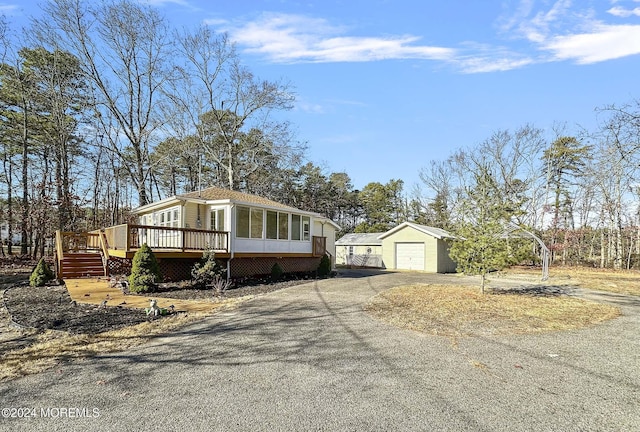 view of front of home with a sunroom, a garage, a deck, and an outbuilding