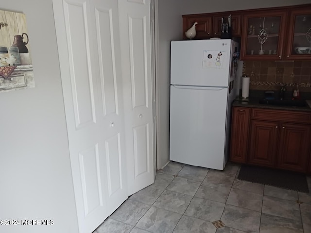 kitchen with backsplash, sink, white fridge, and light tile patterned floors