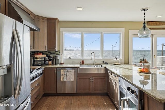 kitchen featuring sink, light stone counters, dark hardwood / wood-style flooring, a water view, and appliances with stainless steel finishes