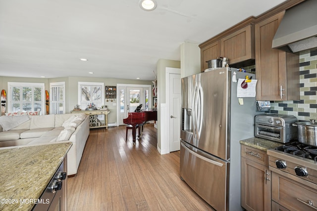 kitchen featuring decorative backsplash, appliances with stainless steel finishes, extractor fan, and a wealth of natural light