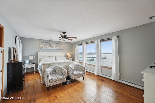 bedroom featuring ceiling fan, light hardwood / wood-style floors, and a baseboard heating unit