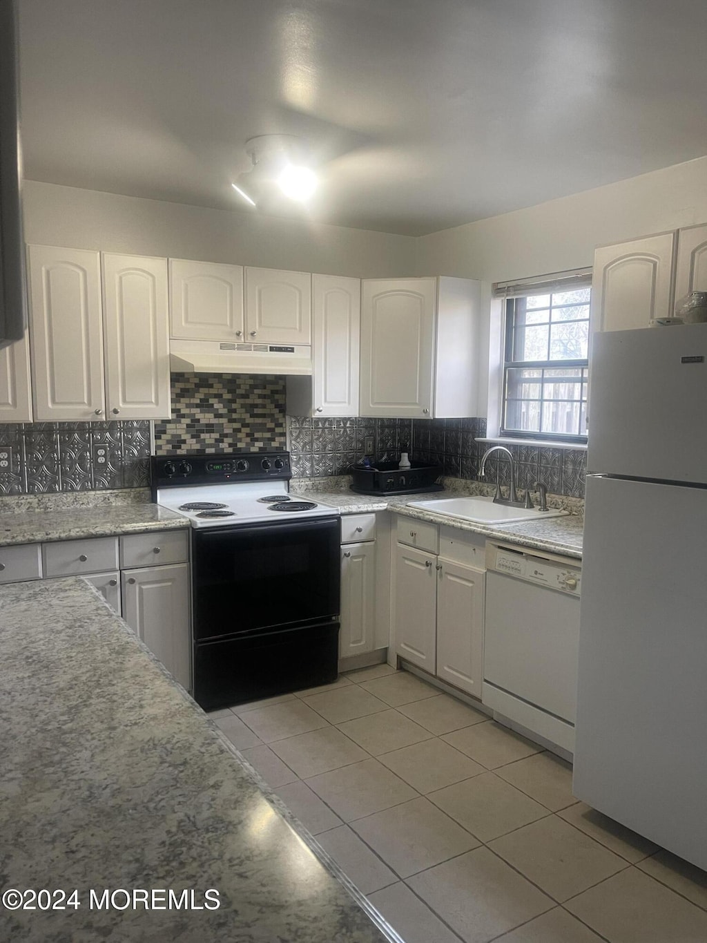 kitchen with white appliances, backsplash, white cabinets, sink, and light tile patterned flooring