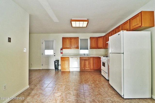 kitchen with light tile patterned floors, white appliances, and sink