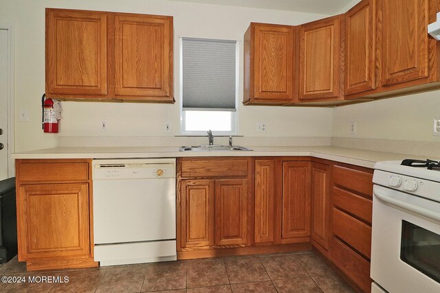 kitchen with white appliances, dark tile patterned flooring, and sink