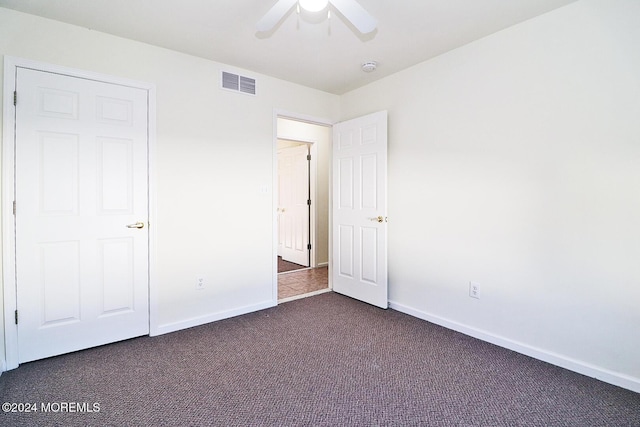 unfurnished bedroom with dark carpet and ceiling fan