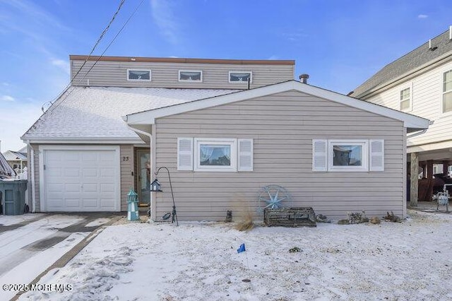 snow covered rear of property with a garage