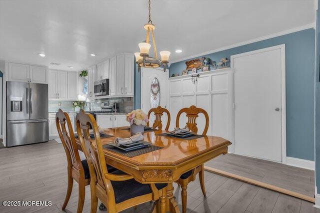 dining area featuring crown molding, light hardwood / wood-style flooring, and a chandelier