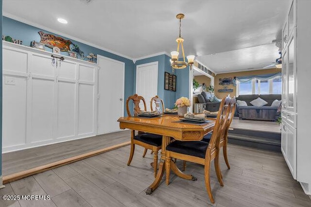 dining space with crown molding, ceiling fan with notable chandelier, and light hardwood / wood-style flooring