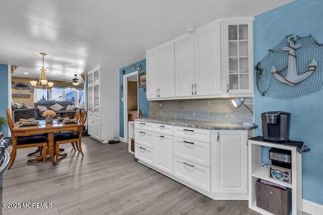 kitchen with tasteful backsplash, light wood-type flooring, hanging light fixtures, and white cabinets