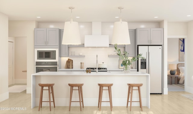 kitchen with stainless steel appliances, a center island with sink, gray cabinetry, and a breakfast bar area