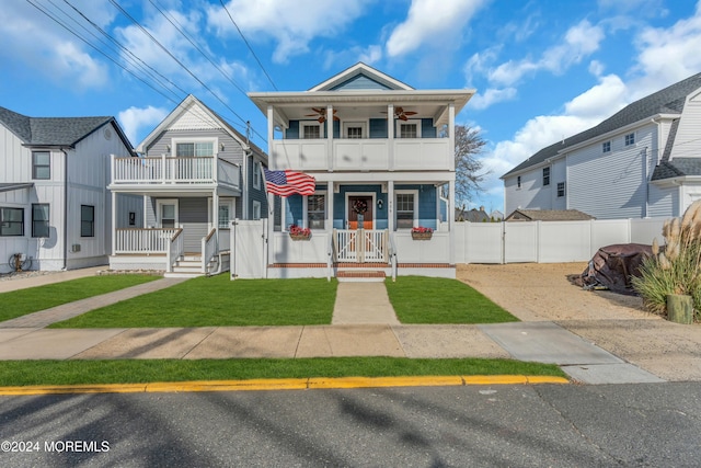 view of front of house featuring covered porch, a balcony, and a front yard