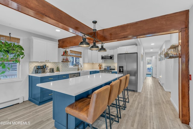 kitchen featuring stainless steel appliances, blue cabinetry, decorative light fixtures, white cabinets, and a center island