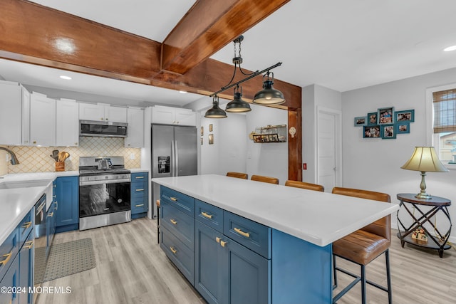 kitchen featuring blue cabinetry, white cabinetry, a kitchen breakfast bar, pendant lighting, and appliances with stainless steel finishes