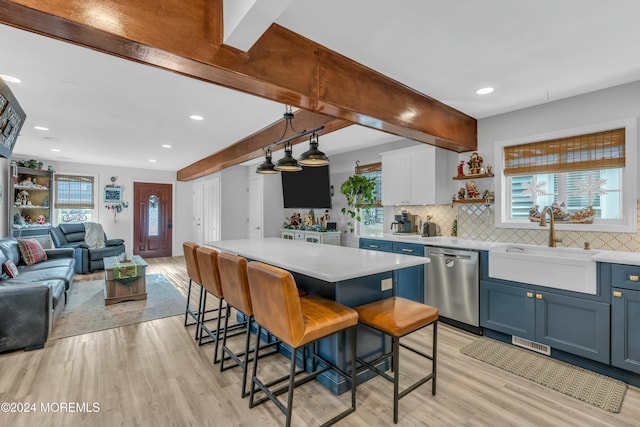 kitchen with light wood-type flooring, stainless steel dishwasher, a breakfast bar, sink, and hanging light fixtures