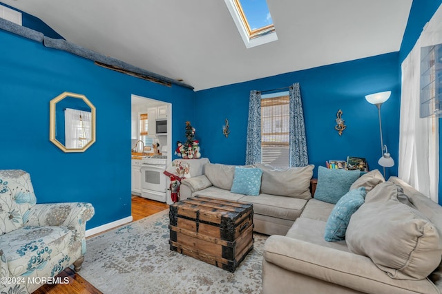 living room with vaulted ceiling with skylight and hardwood / wood-style flooring