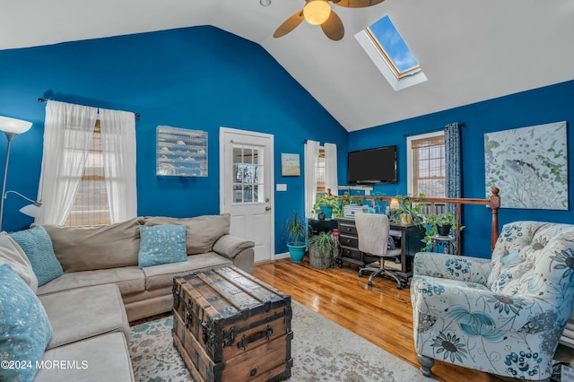 living room featuring ceiling fan, hardwood / wood-style floors, a healthy amount of sunlight, and vaulted ceiling with skylight