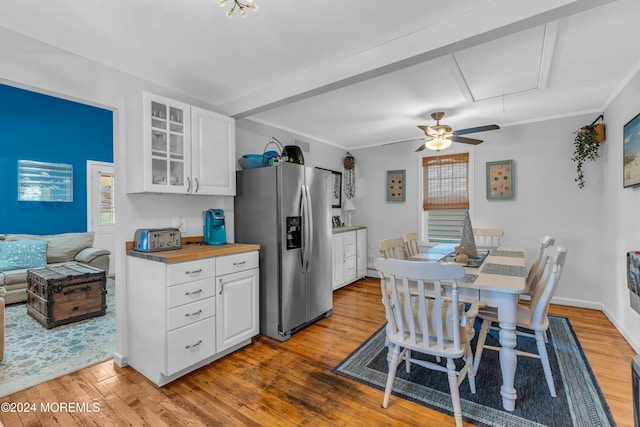 kitchen with hardwood / wood-style floors, butcher block counters, stainless steel fridge with ice dispenser, ornamental molding, and white cabinetry