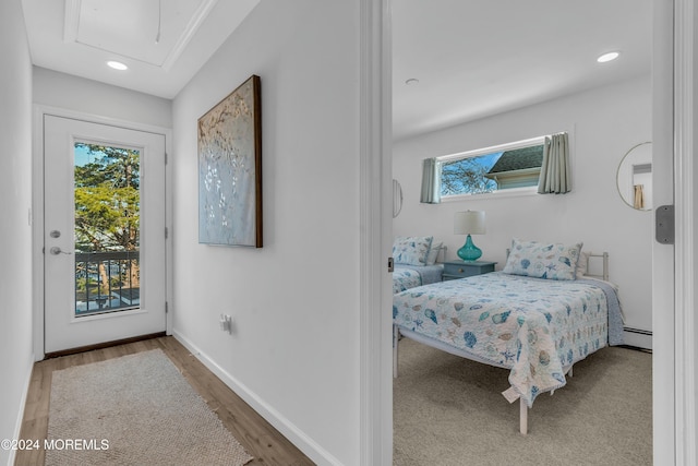 bedroom with hardwood / wood-style floors, access to outside, and a baseboard radiator