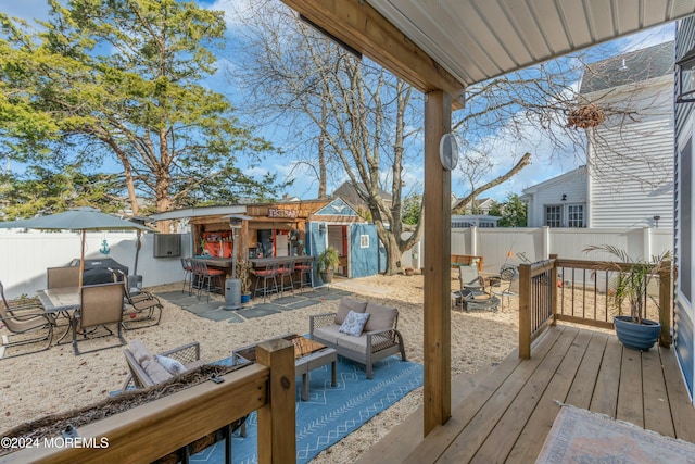 wooden deck featuring an outdoor bar, an outdoor hangout area, and a storage unit