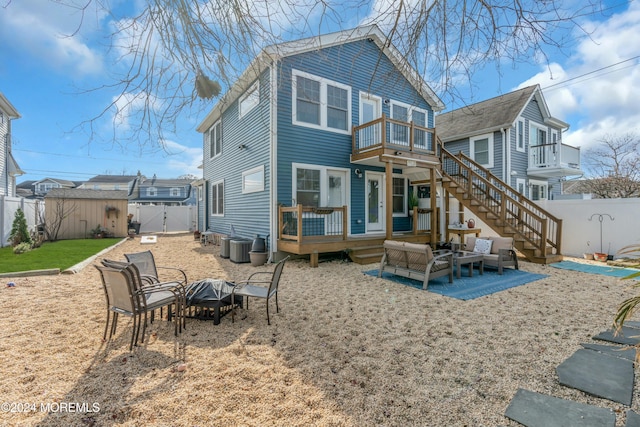 back of house with a deck, a storage unit, a balcony, an outdoor living space with a fire pit, and a patio area