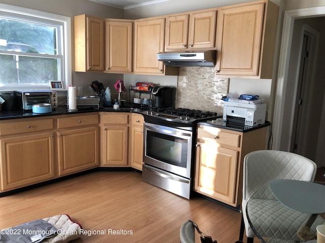 kitchen featuring backsplash, light brown cabinetry, stainless steel gas stove, and light hardwood / wood-style floors