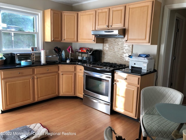 kitchen featuring light wood-type flooring, light brown cabinetry, gas stove, and tasteful backsplash