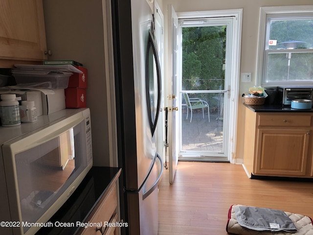 kitchen with stainless steel fridge, light wood-type flooring, and light brown cabinetry