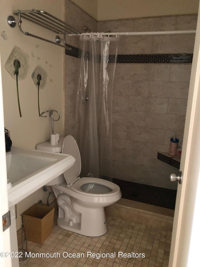 bathroom featuring tile patterned flooring, toilet, and walk in shower