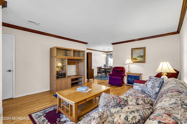 living room with light hardwood / wood-style floors, crown molding, and an inviting chandelier