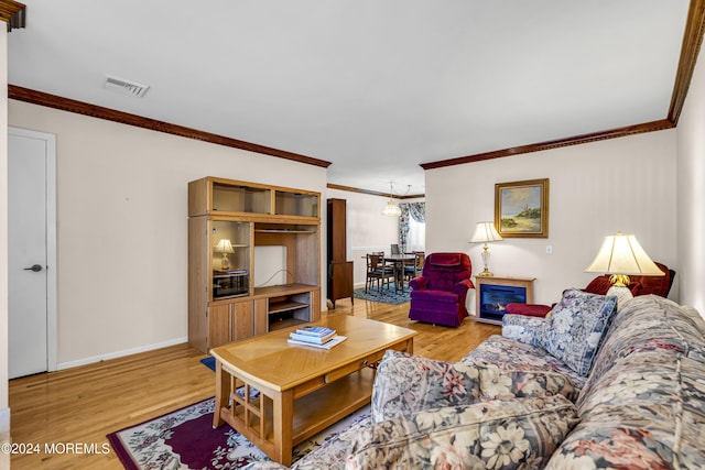 living room featuring a notable chandelier, light hardwood / wood-style floors, and ornamental molding