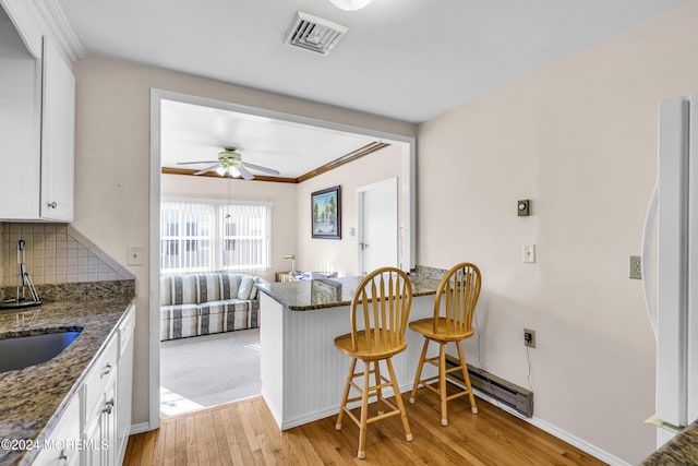 kitchen featuring white cabinets, decorative backsplash, white appliances, and light hardwood / wood-style flooring