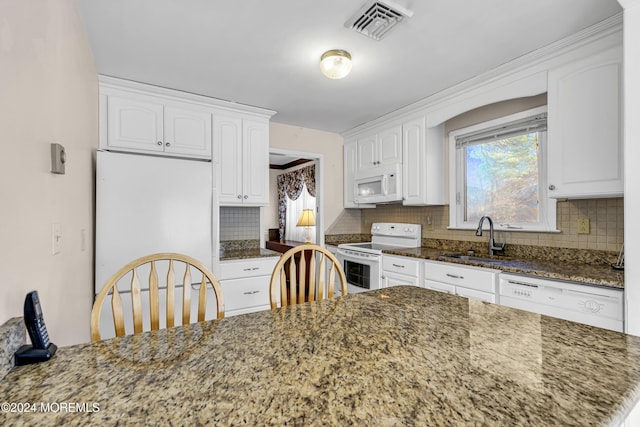 kitchen featuring dark stone countertops, white cabinetry, sink, and white appliances