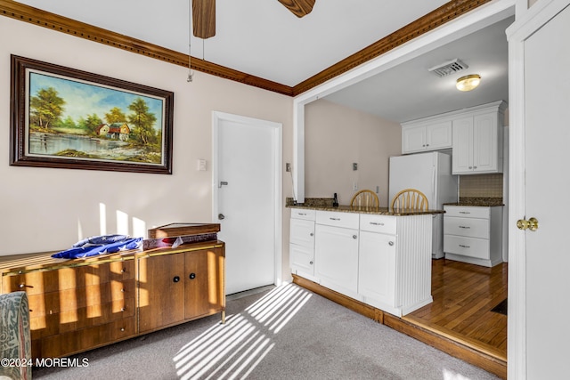 kitchen featuring dark stone counters, white refrigerator, decorative backsplash, white cabinetry, and wood-type flooring