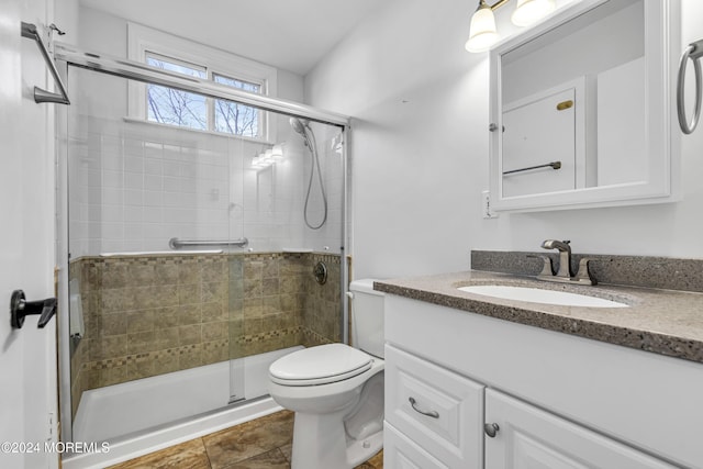 bathroom featuring tile patterned flooring, vanity, toilet, and walk in shower