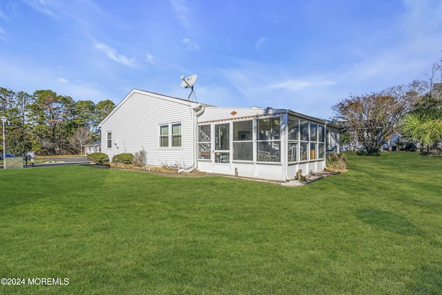 rear view of property featuring a yard and a sunroom