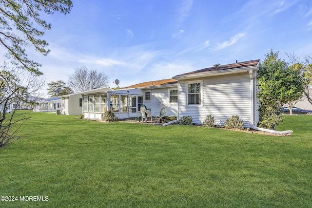 rear view of house with a yard and a sunroom