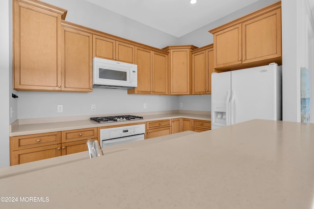 kitchen featuring light brown cabinets and white appliances