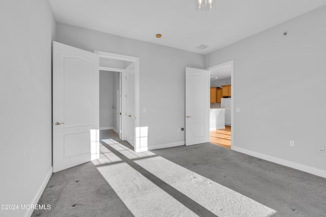 unfurnished bedroom with light carpet and white fridge