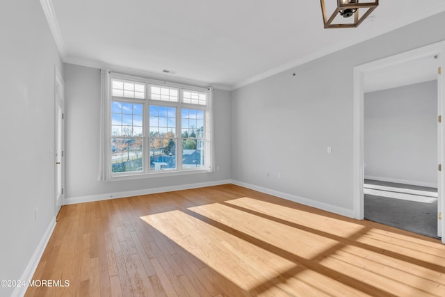 spare room featuring crown molding and light hardwood / wood-style flooring