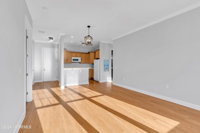 unfurnished living room featuring light hardwood / wood-style floors, crown molding, and a chandelier