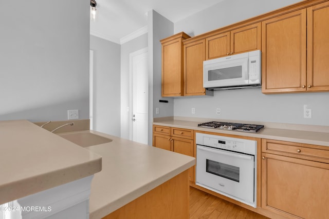 kitchen with sink, ornamental molding, white appliances, and light wood-type flooring