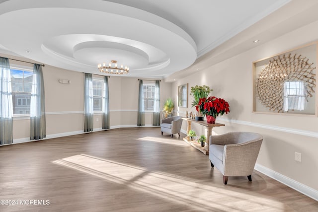 living area with hardwood / wood-style flooring, a chandelier, and a tray ceiling