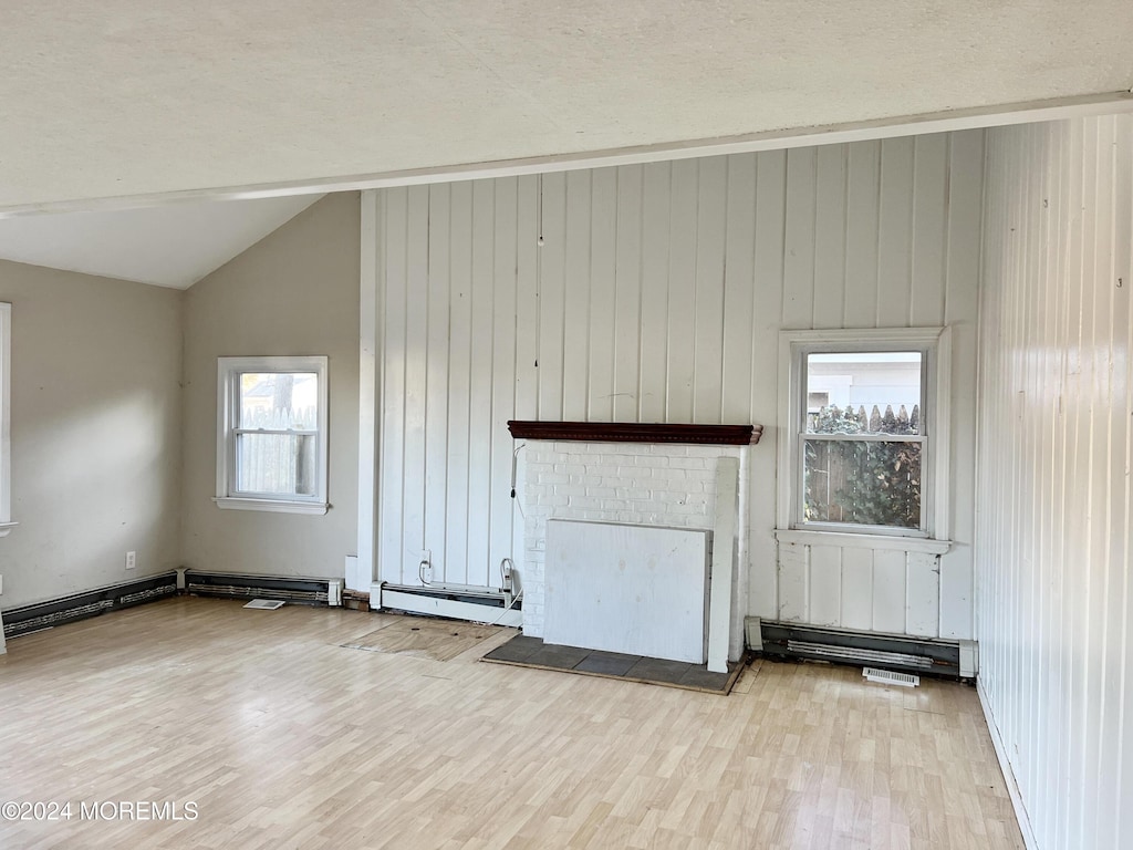unfurnished living room with vaulted ceiling, wood walls, wood finished floors, and a wealth of natural light